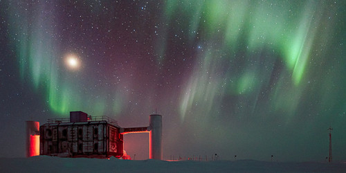 The IceCube neutrino observatory at night with aurorae at the sky